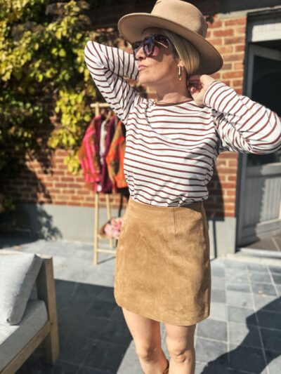 Femme blonde t-shirt rayé blanc et marron jupe daim camel chapeau camel lunettes de soleil